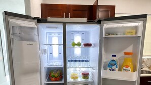 A refrigerator with multiple shelves, containing various food items and beverages. - Acogedora Casa con Excelente Ubicacion (Miami)