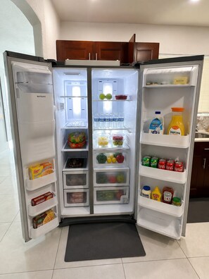 Un réfrigérateur doté de plusieurs étagères, contenant divers aliments et boissons.