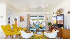 A modern living room with a sofa, yellow chairs, a coffee table, and a TV. - Amarillo  (Palm Springs)