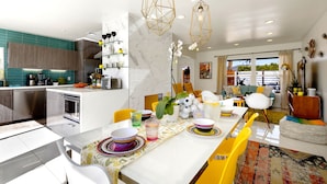 A modern kitchen with a dining area, featuring a marble backsplash, stainless steel appliances, and a central island with seating. - Amarillo  (Palm Springs)