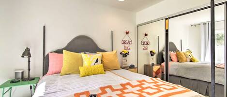 A bedroom with a bed, bedside table, lamp, and a mirror.