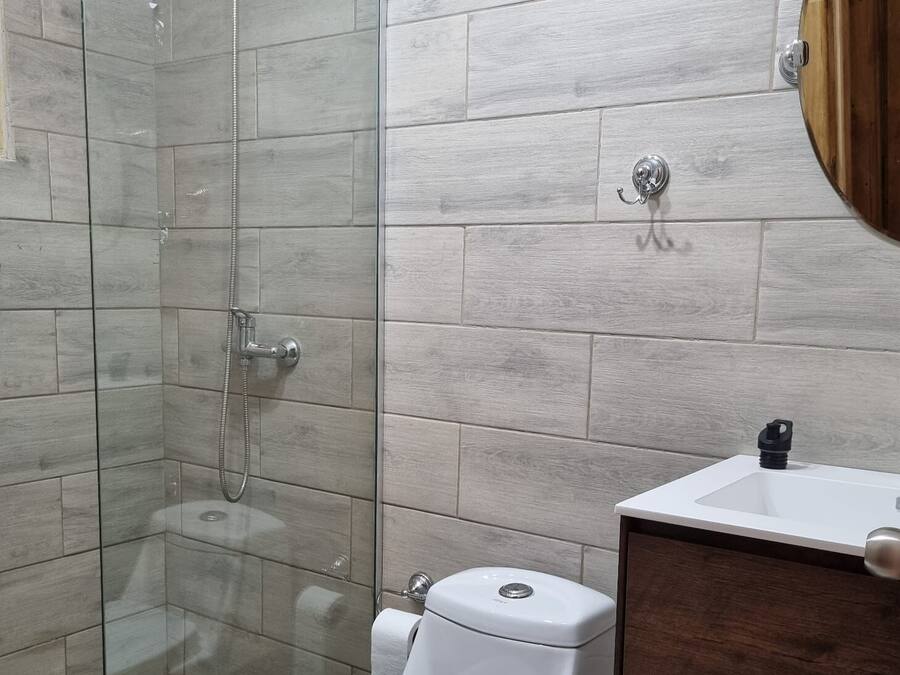 Ein Badezimmer mit Duschkabine, weißer Toilette und einem Holzwaschtisch.