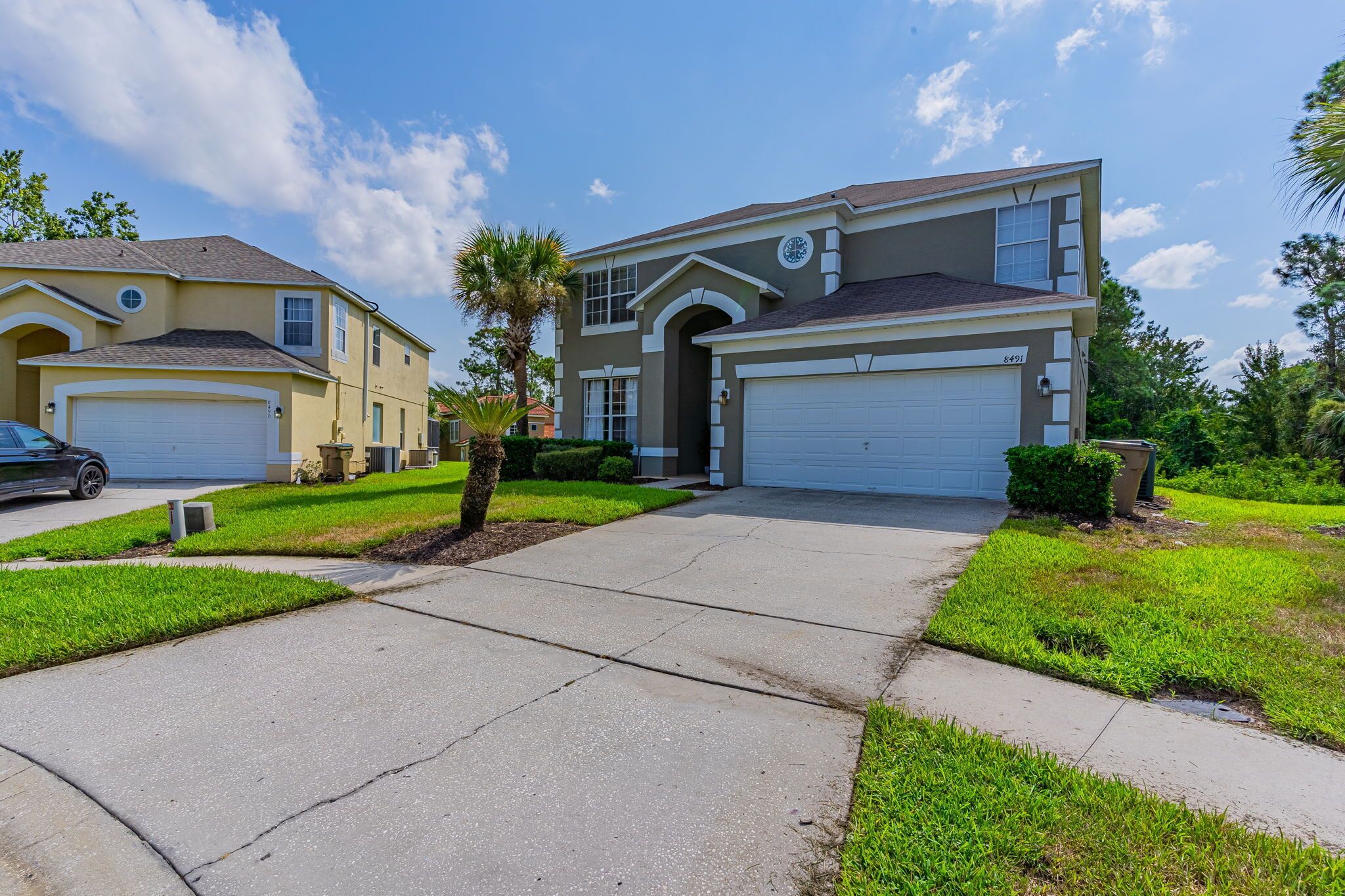A two-story house with a garage, a driveway, and well-maintained lawn.