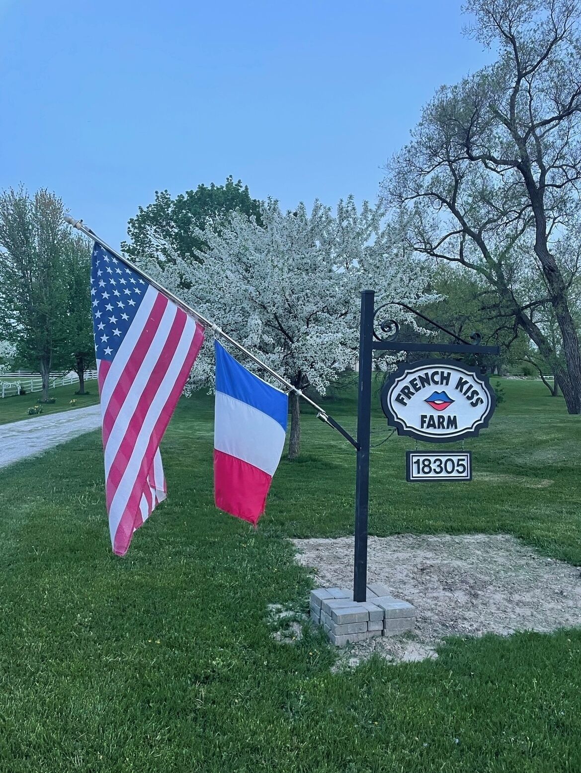A sign for French Kiss Farm with an American and French flag.