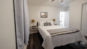 Une chambre à coucher avec un lit, des lampes de chevet, un ventilateur de plafond et un tableau au mur.