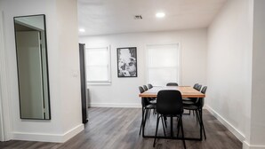 Une salle de conférence avec une table en bois, des chaises noires et un grand miroir sur le côté gauche.