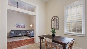 Un comedor con una mesa y sillas de madera, una planta en maceta y vistas a una ventana con persianas.
