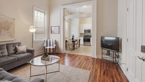 Una sala de estar con sofá, sillón, mesa de centro y mueble para televisión.