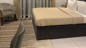 Une chambre à coucher comprenant un lit, une chaise, une table de chevet et deux tableaux encadrés accrochés au mur.