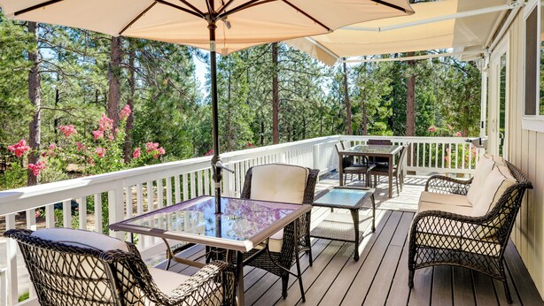 A deck with outdoor furniture, including a table and chairs, and a large umbrella providing shade. - Groveland Vacation Rental w/ Private Deck & Grill! (Groveland)