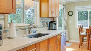 A kitchen with wooden cabinets, a stainless steel sink, and a coffee maker. - Groveland Vacation Rental w/ Private Deck & Grill! (Groveland)