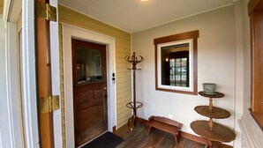 A wooden door with a glass panel, a coat rack, a small bench, and a window with a view of the street. - Cozy Cole St Home built in 1910 in Downtown Enumclaw (Enumclaw)