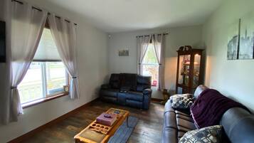 A living room with a sofa, a coffee table, and a window with curtains.