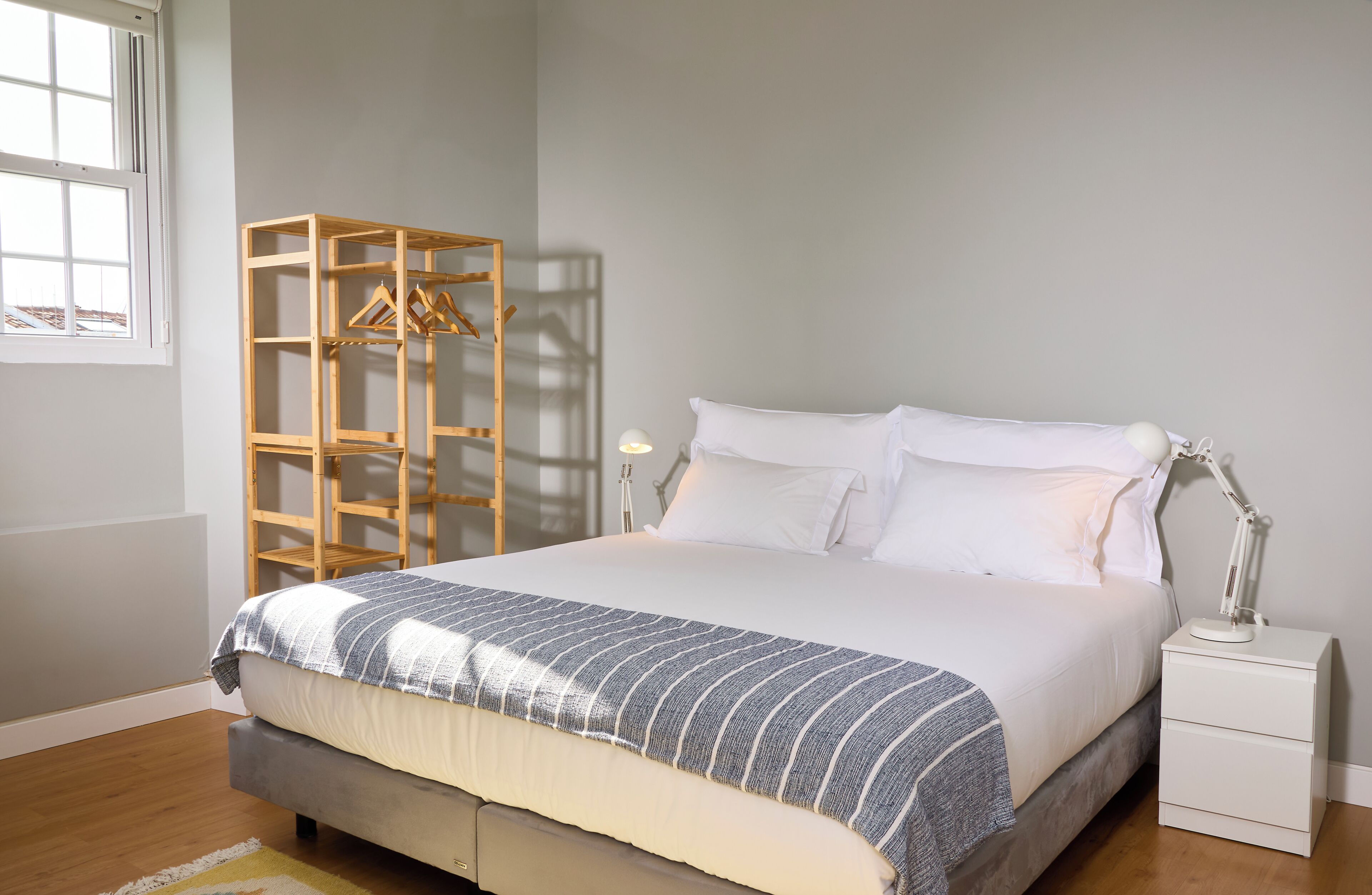 Une chambre à coucher avec un lit, une table de chevet avec une lampe, une armoire en bois et une fenêtre.