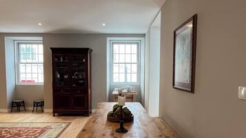 A spacious room with a wooden dining table, benches, a cabinet, and a large window.