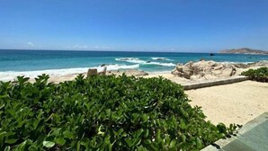 Ein Strand mit klarem, blauem Wasser, Felsformationen und grüner Vegetation.