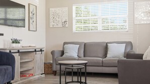 Ein Wohnzimmer mit einem grauen Sofa, einem kleinen runden Tisch und einem blauen Sessel.