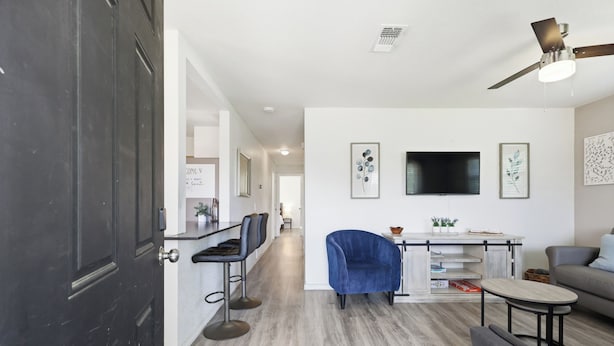 Ein modernes Interieur mit Essbereich, einer Couch, einem Fernseher und Deckenventilator.