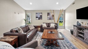 A modern living room with a brown leather sofa, a wooden coffee table, and a television on the wall.