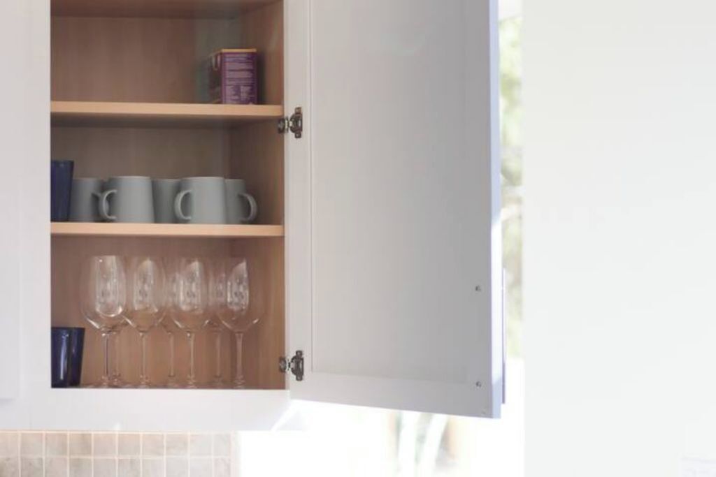 Un mueble con repisas que contiene tazas y vasos.