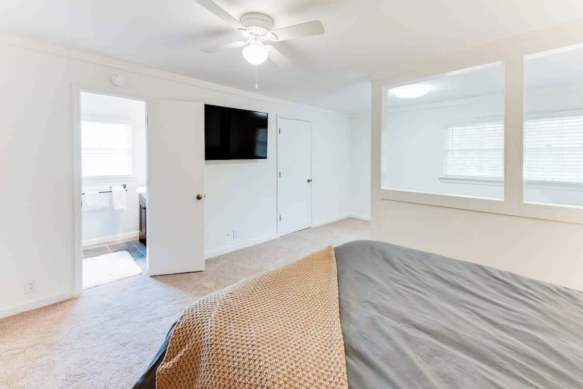 A bedroom with a bed, a ceiling fan, a TV, and a wardrobe.