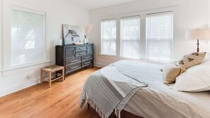 A bedroom with a bed, a dresser, a bench, and a ceiling fan.