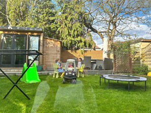 Enjoy an outdoor space with a lawn, trampoline, playhouse, and shaded areas.