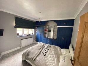 Cozy retreat with a neatly made bed, blue accent wall, and shelving.