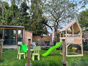 Enjoy a backyard retreat with a playhouse, dining area, and play structure surrounded by a lush lawn.