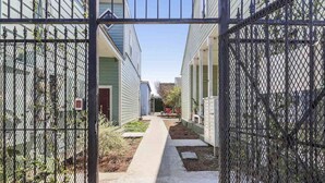 A gated courtyard with a concrete pathway leading to a row of buildings. - Cute centrally located 1bed 1bath walk to French Q, Bourbon St & Jazz venues  (New Orleans)