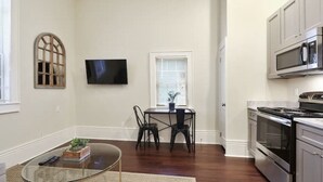 A modern kitchen with stainless steel appliances, a dining area with a table and chairs, and a television mounted on the wall. - Cute centrally located 1bed 1bath walk to French Q, Bourbon St & Jazz venues  (New Orleans)