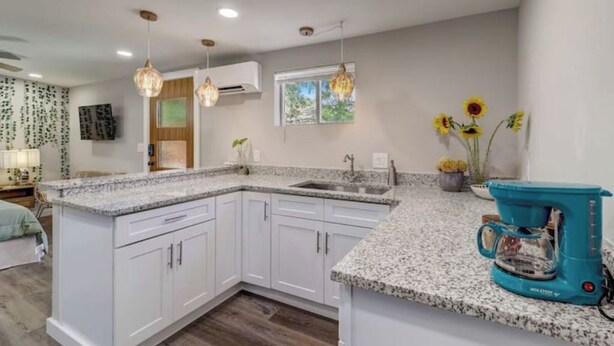 A modern kitchen with white cabinets, granite countertops, and a built-in coffee maker. - The Southtown Hummingbird Haus (San Antonio)