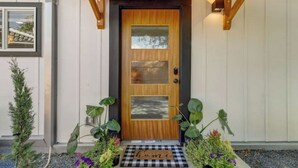 A wooden front door with a glass panel and a doormat that reads "home". - The Southtown Hummingbird Haus (San Antonio)