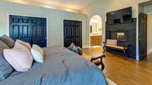 A bedroom with a large bed, two doors, a fireplace, and a TV mounted above it. - 1 Mi to Water Ranch! Family Retreat w/ Resort Pool (Gilbert)