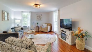 Ein Wohnzimmer mit Sofa, Sessel, Fernseher und einer dekorativen Vase.