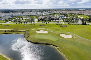 An aerial view of a golf course with sand bunkers, a pond, and surrounding residential buildings. - Amazing Resort, Private Pool! (Davenport)