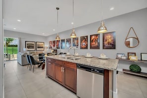 A modern kitchen with a granite countertop, stainless steel appliances, and pendant lighting.
