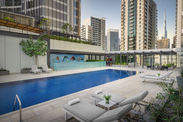 A rooftop swimming pool with lounge chairs and a mural, surrounded by high-rise buildings. - Holiday Inn Dubai Business Bay by IHG (Dubai)