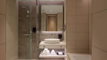 A modern bathroom with a glass-enclosed shower, a large sink, and a vanity with towels and toiletries.