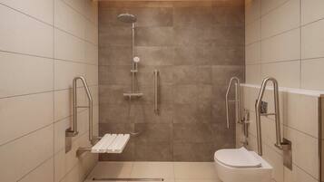 Une salle de bain moderne équipée d’une douche, de toilettes et de barres d’appui.