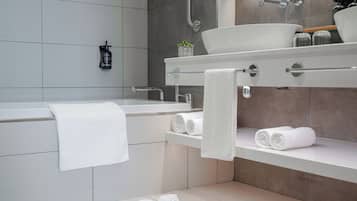 A modern bathroom with a bathtub, a large sink, and a shelf with towels.