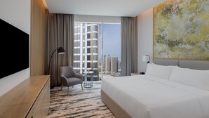 A hotel room with a large bed, a desk, a chair, a small table, and a large window with a city view. - Holiday Inn Dubai Business Bay by IHG (Dubai)