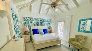 A bedroom with a bed, nightstands, a chair, and a ceiling fan. - Tropical Oasis with Pool close to beach - Beachcomber (Sunset Crest)