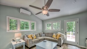 A living room with a sectional sofa, a coffee table, a side table with a lamp, and a ceiling fan.