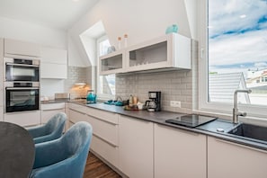 A modern kitchen with built-in appliances, a window with a view, and a dining area with a chair.