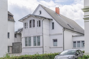En tvåvånings bostadsbyggnad med ett sadeltak, flera fönster och en synlig skorsten.