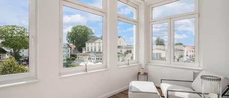 Ett rum med stora fönster, en kristallkrona och utsikt över ett bostadsområde.
