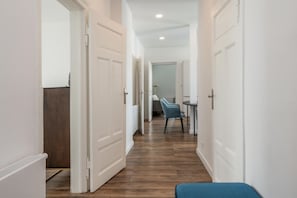 A hallway with white doors, a dining area with chairs, and a blue bench.