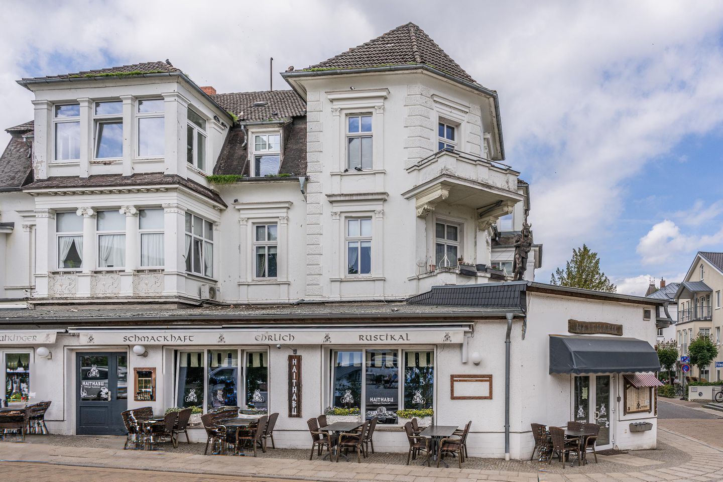 A multi-story building with a ground-floor restaurant featuring outdoor seating.