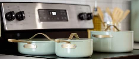 Une cuisine équipée d’un four en acier inoxydable et de trois casseroles bleu clair sur la cuisinière.
